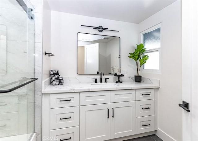 full bathroom with vanity, a shower with shower door, and baseboards