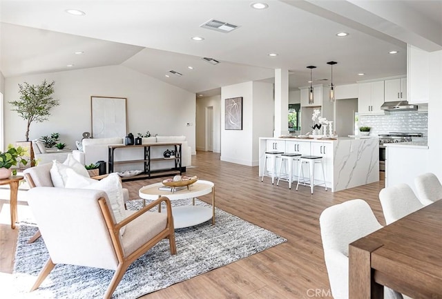 living area with light wood-style flooring, recessed lighting, visible vents, baseboards, and vaulted ceiling