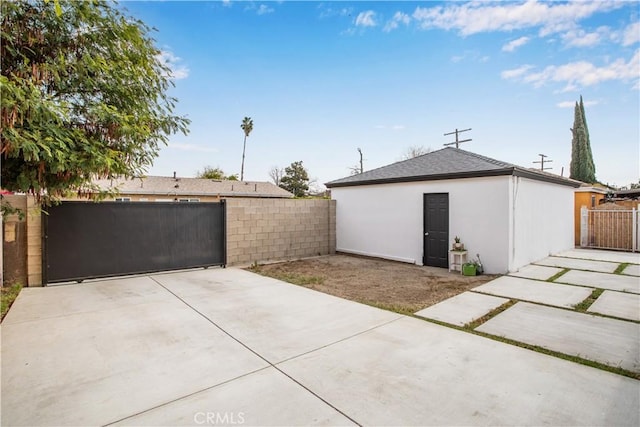 garage with concrete driveway, fence, and a gate