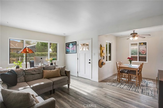 living room featuring baseboards, a ceiling fan, and wood finished floors