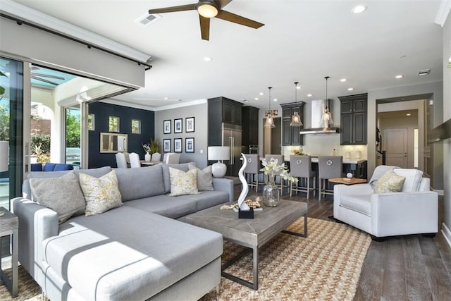 living room featuring dark wood finished floors, recessed lighting, visible vents, ornamental molding, and a ceiling fan