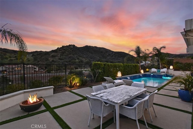 view of pool featuring outdoor dining area, a mountain view, a fire pit, fence, and a patio area