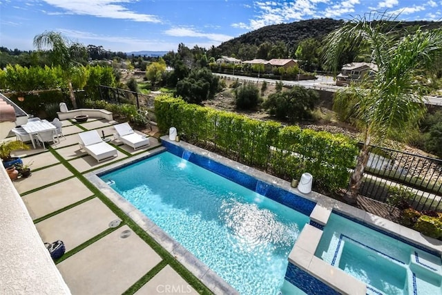 view of swimming pool with a patio area, a pool with connected hot tub, and fence