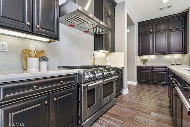 kitchen featuring range with two ovens, dark wood-style floors, tasteful backsplash, visible vents, and wall chimney exhaust hood