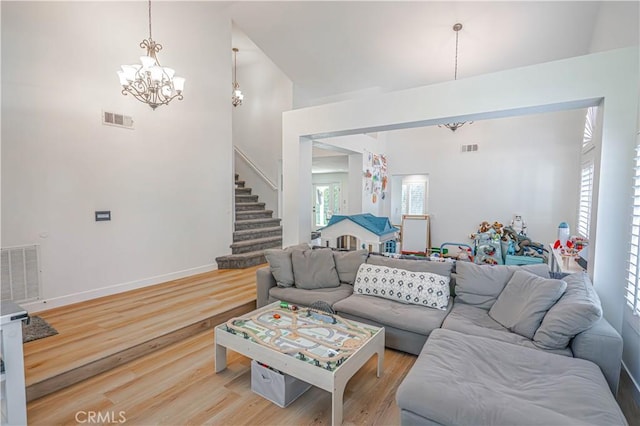 living room with visible vents, a notable chandelier, light wood finished floors, and stairs