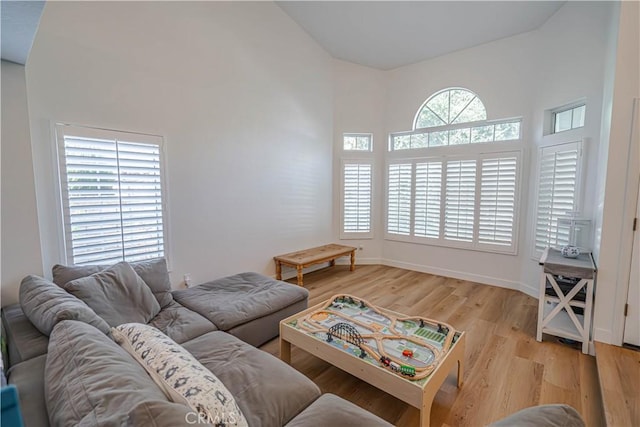 living room with baseboards, vaulted ceiling, and light wood-style floors