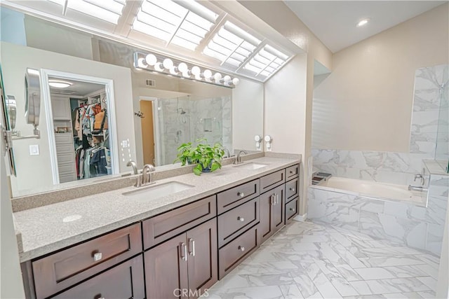 bathroom featuring a garden tub, marble finish floor, a sink, and a marble finish shower