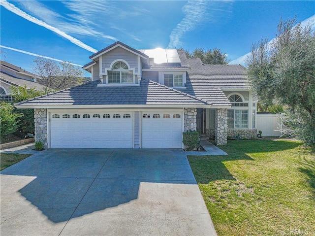 traditional-style home with concrete driveway, a front lawn, an attached garage, and stone siding