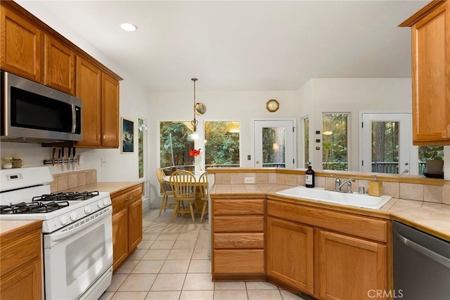 kitchen featuring tile counters, light tile patterned floors, appliances with stainless steel finishes, and a sink