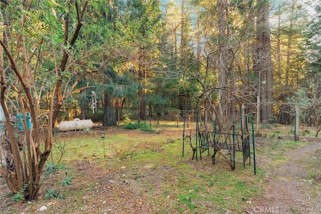 view of yard featuring a wooded view and fence