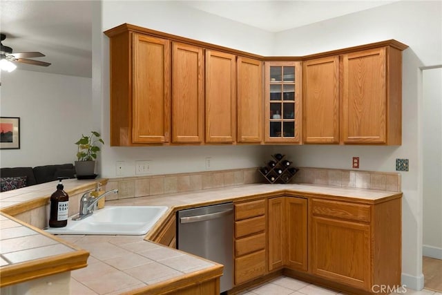 kitchen featuring a sink, brown cabinets, dishwasher, and tile countertops