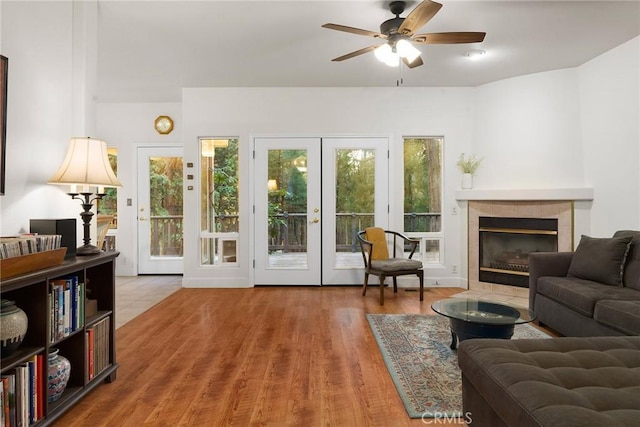 living room with a tile fireplace, plenty of natural light, french doors, and wood finished floors