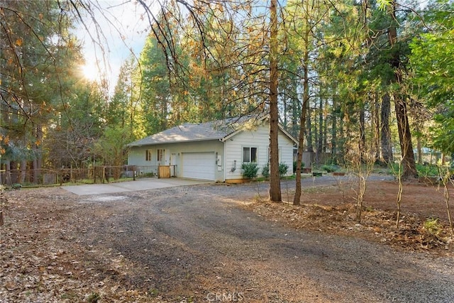 view of side of home with driveway, a garage, and fence