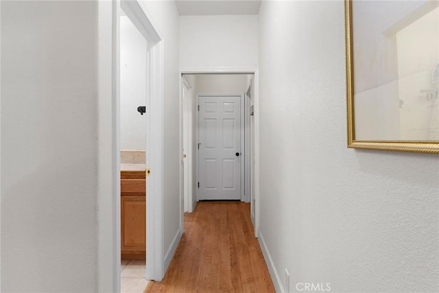 hallway with baseboards and light wood-style flooring