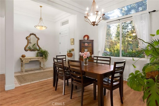 dining space featuring visible vents, light wood-style floors, crown molding, baseboards, and a chandelier