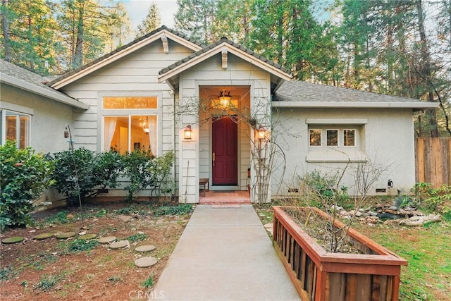 view of front facade featuring crawl space, stucco siding, roof with shingles, and fence