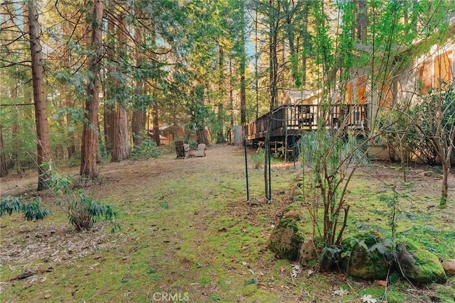 view of yard featuring a wooded view and a deck