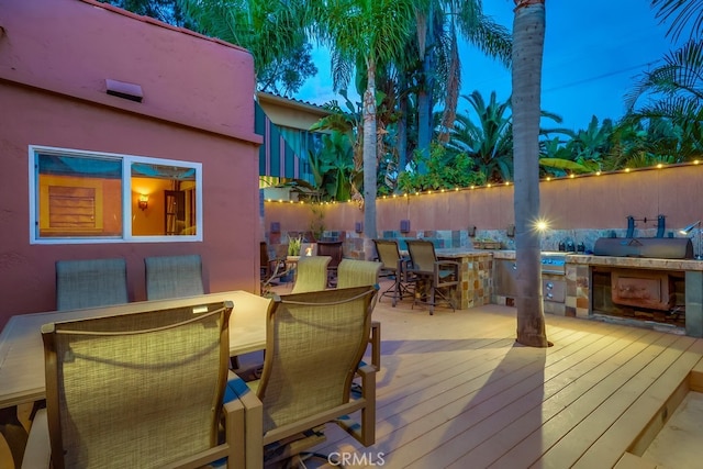 wooden deck with exterior kitchen, outdoor dining area, and fence