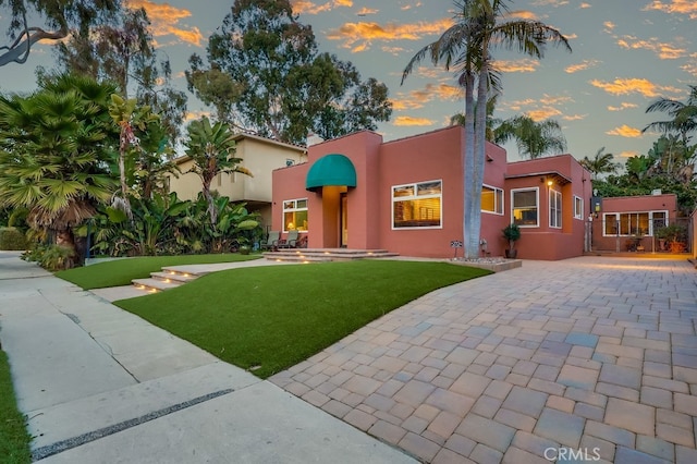 view of front of home with a lawn, decorative driveway, and stucco siding