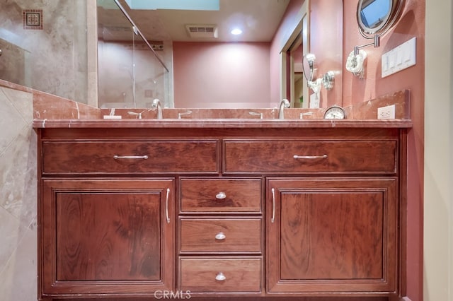 full bathroom featuring double vanity, visible vents, walk in shower, and a sink