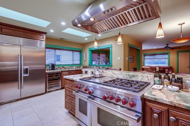 kitchen with premium appliances, wine cooler, a skylight, recessed lighting, and wall chimney exhaust hood