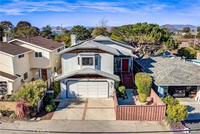 view of front of property with a chimney, an attached garage, fence, a mountain view, and driveway