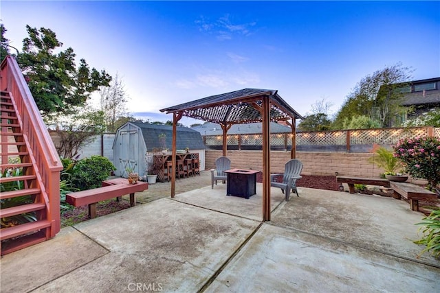 view of patio / terrace featuring a fire pit, a fenced backyard, stairway, an outbuilding, and a storage unit