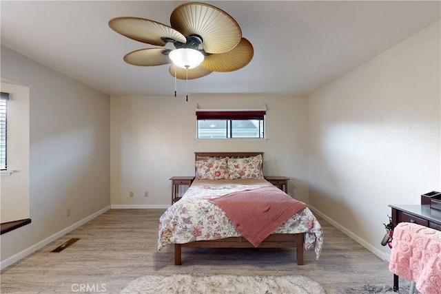 bedroom with baseboards, ceiling fan, visible vents, and light wood-style floors