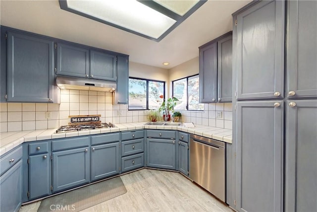 kitchen featuring gas cooktop, light wood-style flooring, under cabinet range hood, dishwasher, and tasteful backsplash