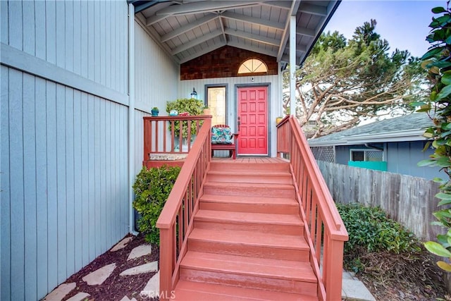 view of exterior entry featuring fence and a porch