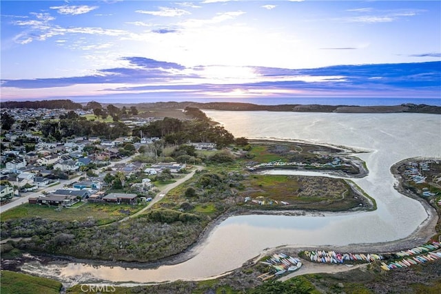 aerial view at dusk featuring a water view