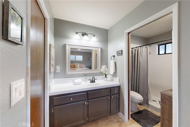 full bathroom with a tile shower, vanity, and toilet