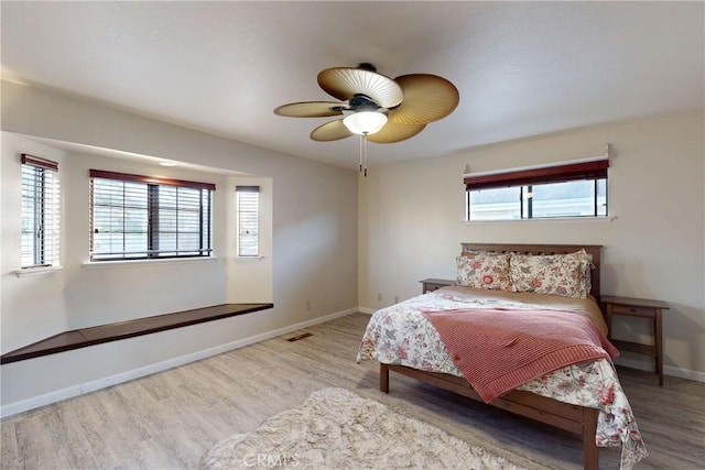 bedroom with visible vents, multiple windows, baseboards, and wood finished floors