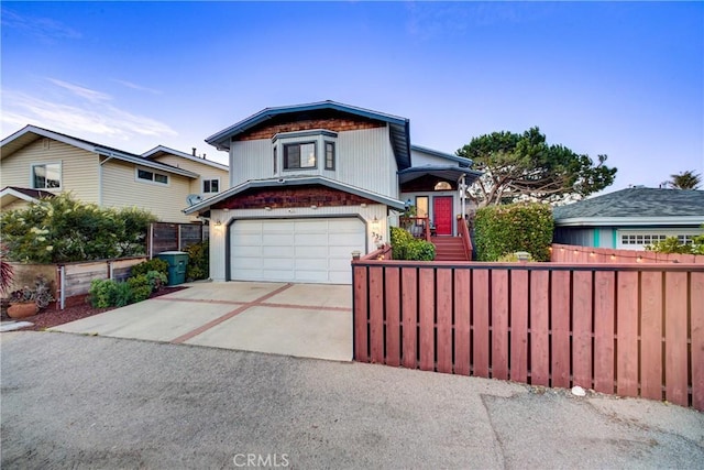 view of front of house with driveway, a garage, and fence