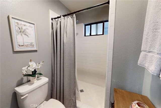 bathroom with toilet, a stall shower, and a textured wall