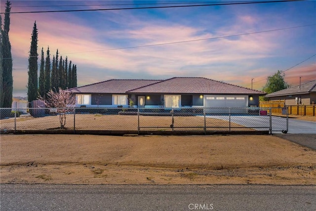 view of front of house with driveway, a fenced front yard, a tile roof, and an attached garage