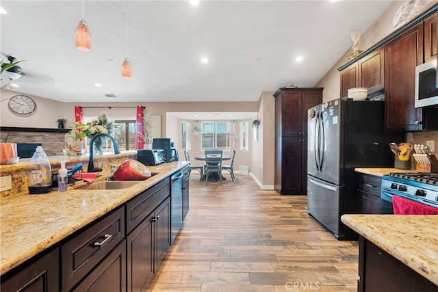 kitchen featuring light wood-style flooring, appliances with stainless steel finishes, dark brown cabinets, and a sink