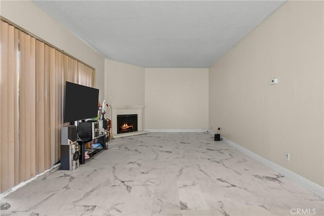 unfurnished living room featuring a warm lit fireplace, marble finish floor, a textured ceiling, and baseboards