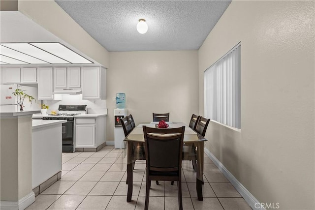 dining space with a textured ceiling, light tile patterned flooring, and baseboards