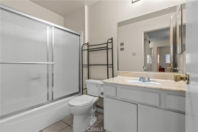 full bathroom with bath / shower combo with glass door, vanity, toilet, and tile patterned floors