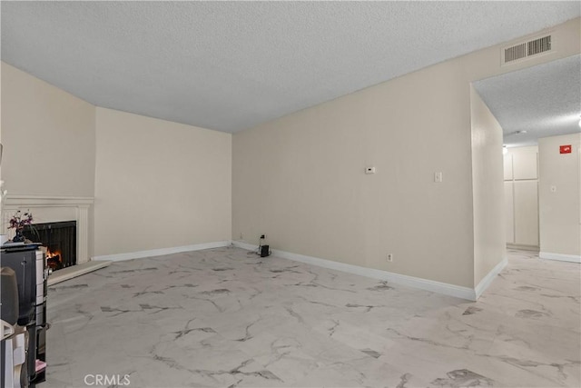 unfurnished living room featuring marble finish floor, visible vents, a textured ceiling, a lit fireplace, and baseboards