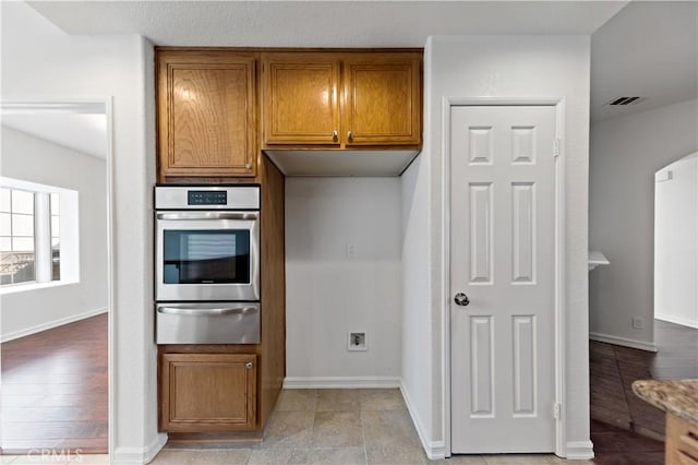 kitchen with visible vents, arched walkways, brown cabinetry, oven, and a warming drawer