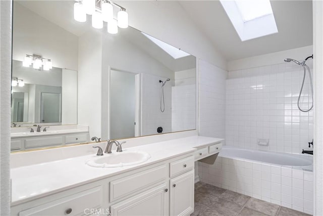 full bathroom featuring lofted ceiling with skylight, vanity, tiled shower / bath, and tile patterned floors