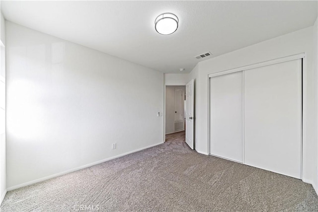 unfurnished bedroom with carpet, a closet, visible vents, and baseboards