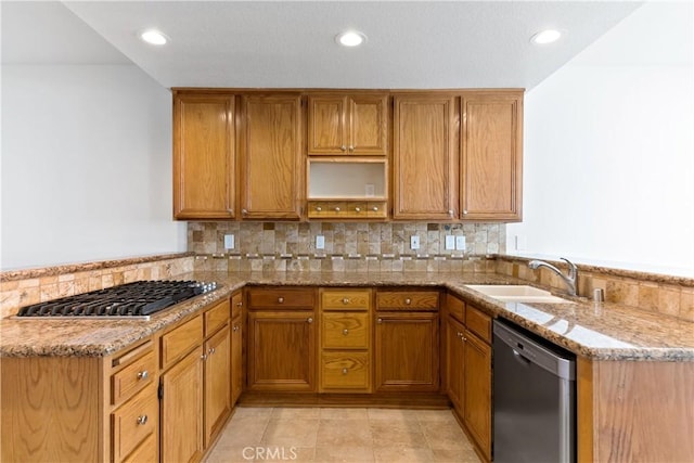 kitchen featuring stainless steel appliances, a peninsula, a sink, and light stone countertops