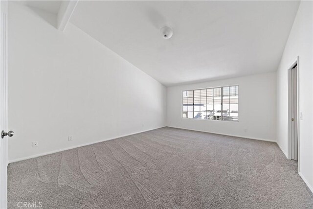 carpeted spare room featuring lofted ceiling with beams and baseboards