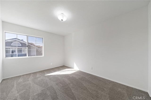 carpeted spare room featuring baseboards