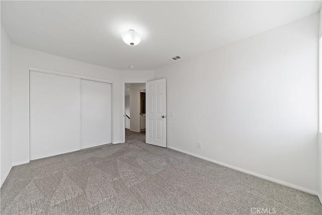 unfurnished bedroom featuring baseboards, a closet, visible vents, and carpet flooring