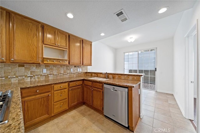 kitchen featuring light stone counters, stainless steel appliances, visible vents, brown cabinetry, and a sink