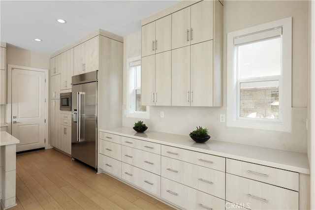 kitchen featuring built in appliances, recessed lighting, light countertops, and light wood-type flooring